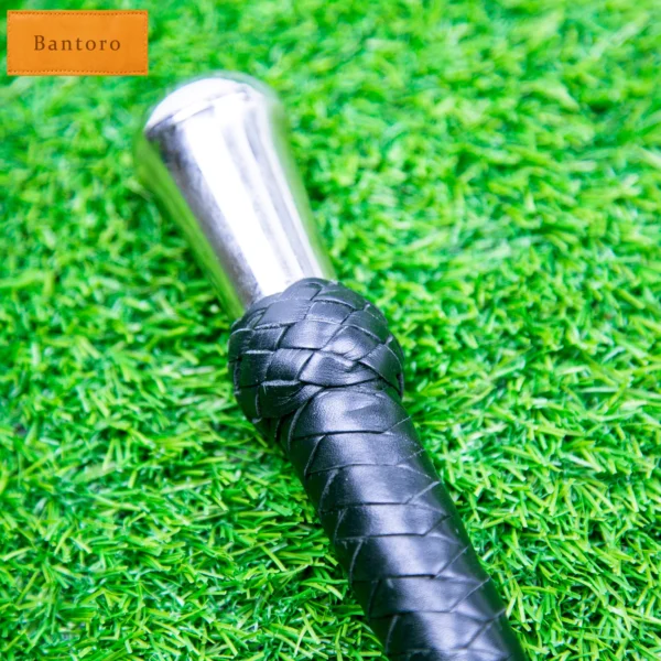 leather bdsm crop handle close-up with metal top and braided grip