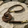 Leather dog leash 2.5M brown lead coiled on stone with brass clips and adjustable attachment rings